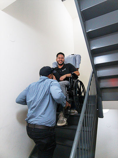 A person helping someone in a wheelchair safely navigate stairs